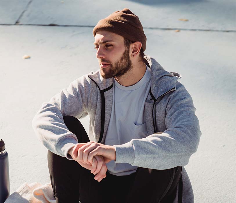 A bearded sportsman resting on street with claspad hands