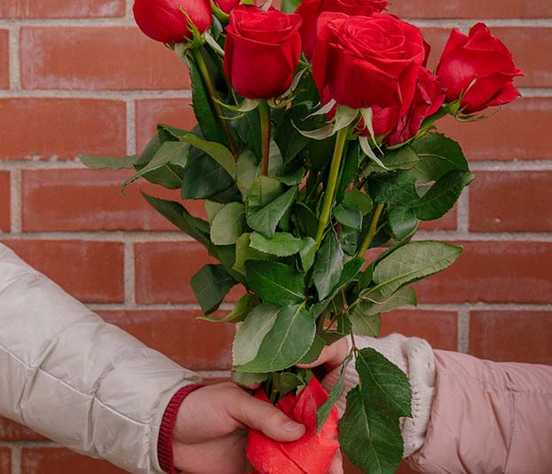 A boyfriend and a girlfriend with bright red bouquet of roses