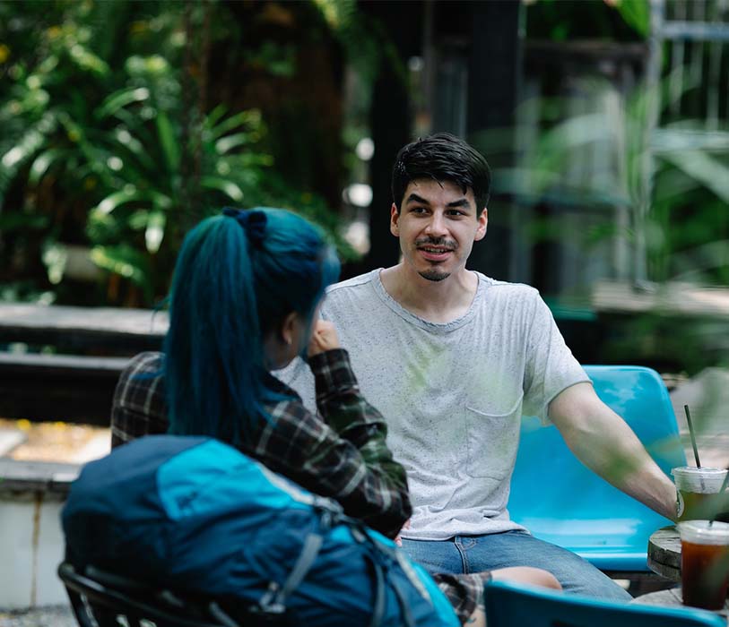 A cheerful ethnic man with girlfriend resting in outdoor cafe