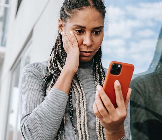 A concerned black woman using smartphone on street