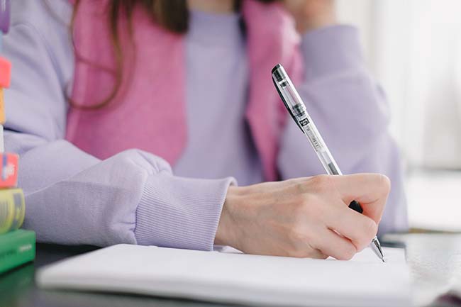 A girl is writing something on a paper.