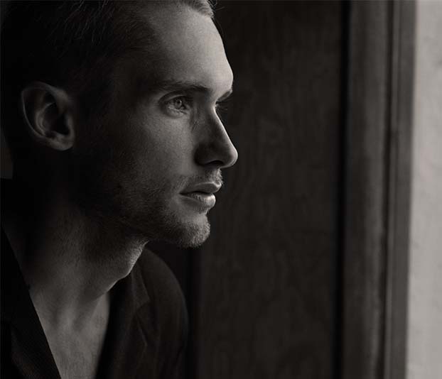 A grayscale photo of man facing glass panel