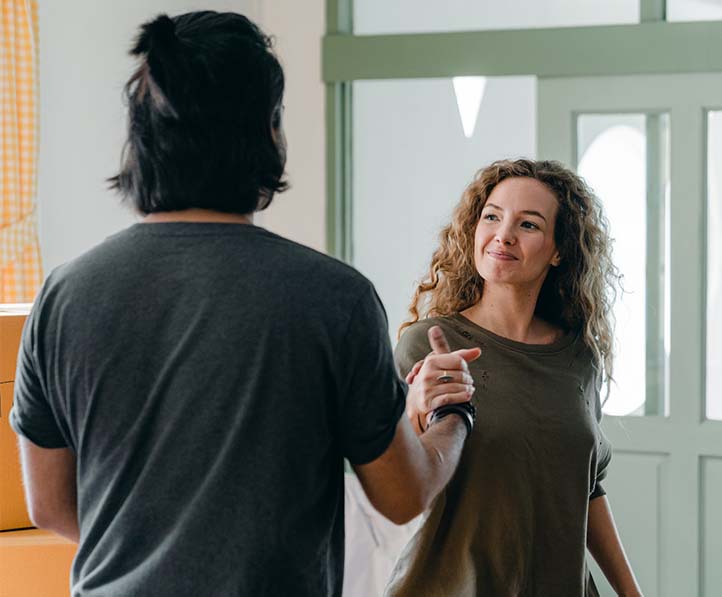 A happy couple shaking hands to each other in an apartment