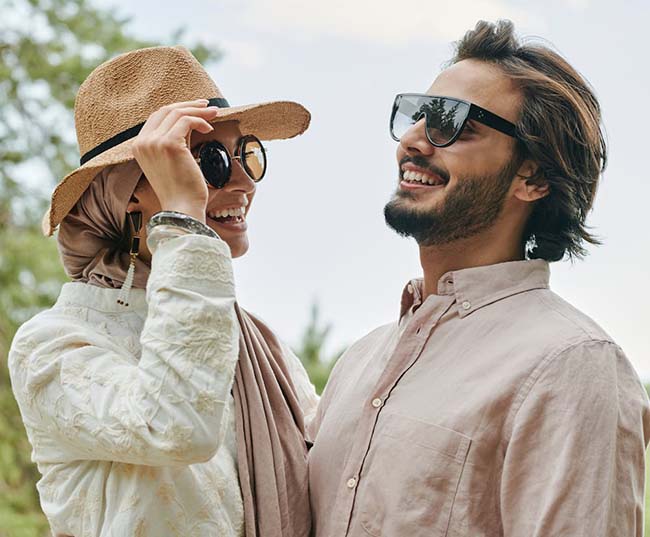 A laughing man and a woman wearing sunglasses 