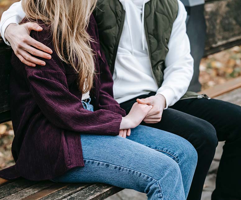 A loving couple holding each other hands sitting on a bench