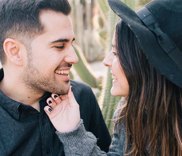 A man and a woman are holding hands smiling at each other.