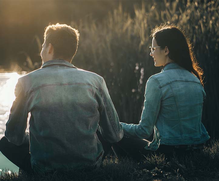 A man and a woman sitting near the body of water