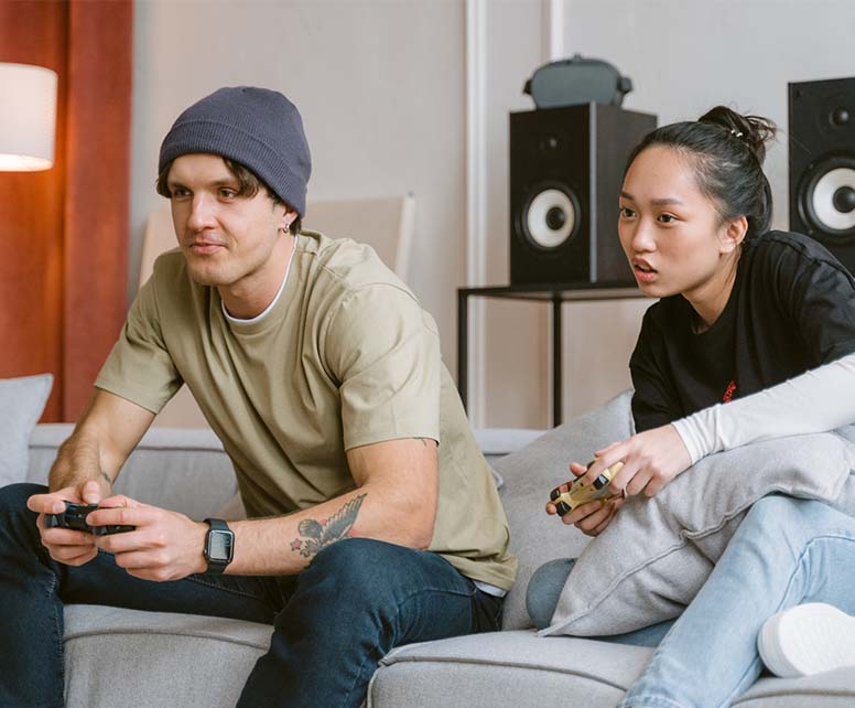 A man and a woman sitting on the couch while playing video game