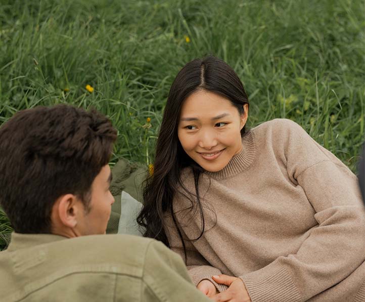 A man and a woman staring at each other while lying on the grass