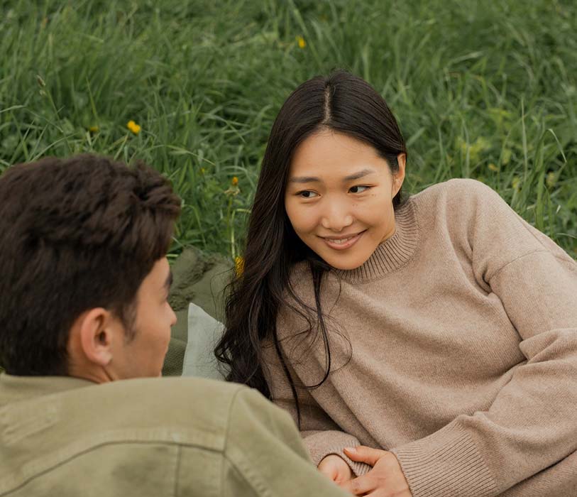 A man and a woman staring at each other while lying on the grass