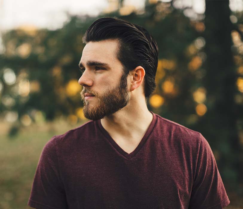 A man captured his photo in forest wearing maroon v-neck t-shirt