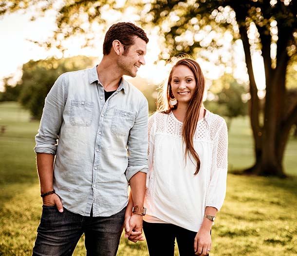 A man holding a hand of a woman standing near a tree