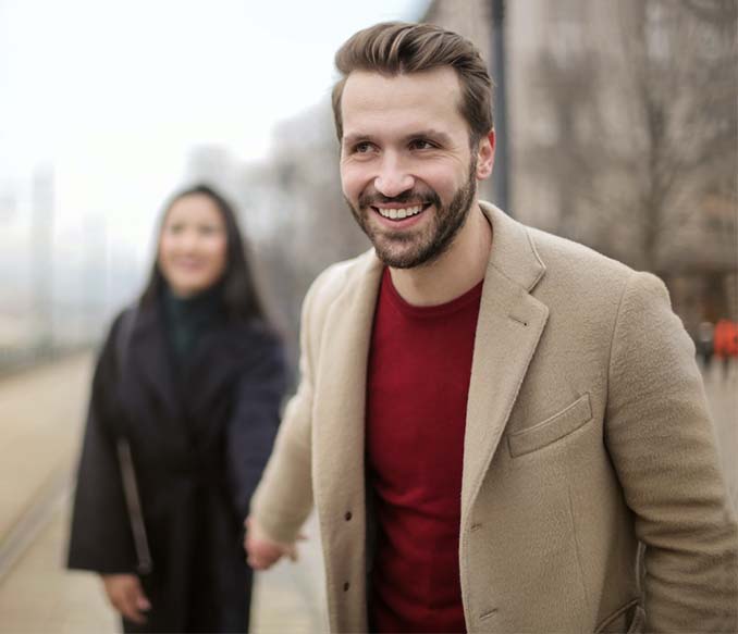 A man in a brown and woman in black coat standing on sidewalk