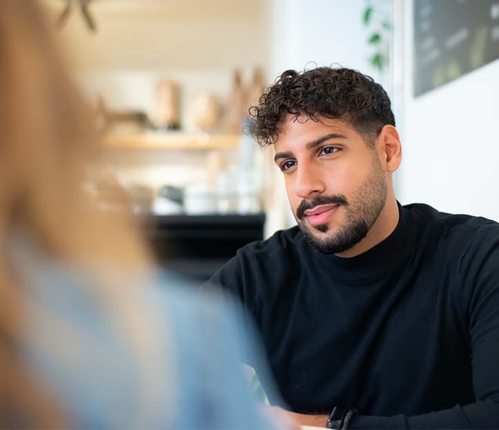 A man in black long sleeves looking at the person in front of him