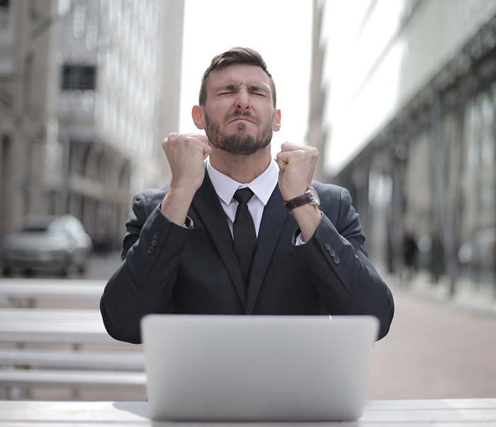 A man in black suit sitting on chair beside buildings