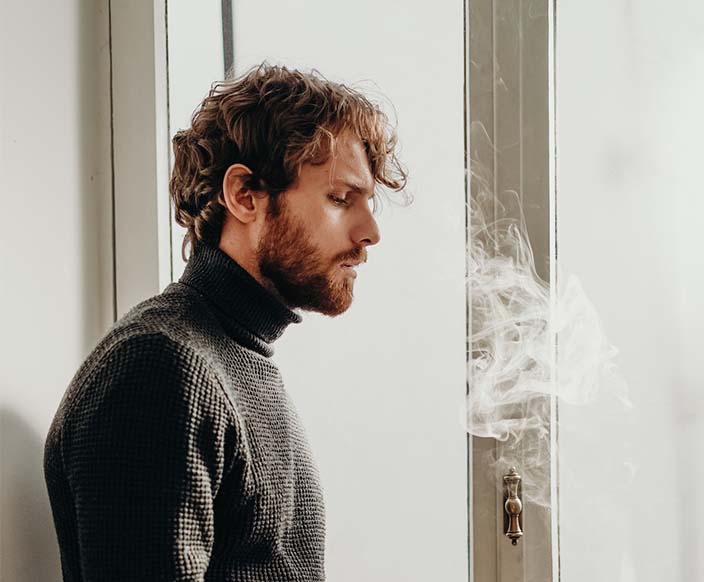 A man in black sweater standing beside a white wooden door