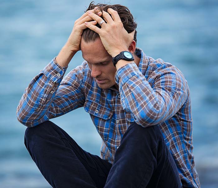 A man in blue and brown plaid dress shirt touching his hair