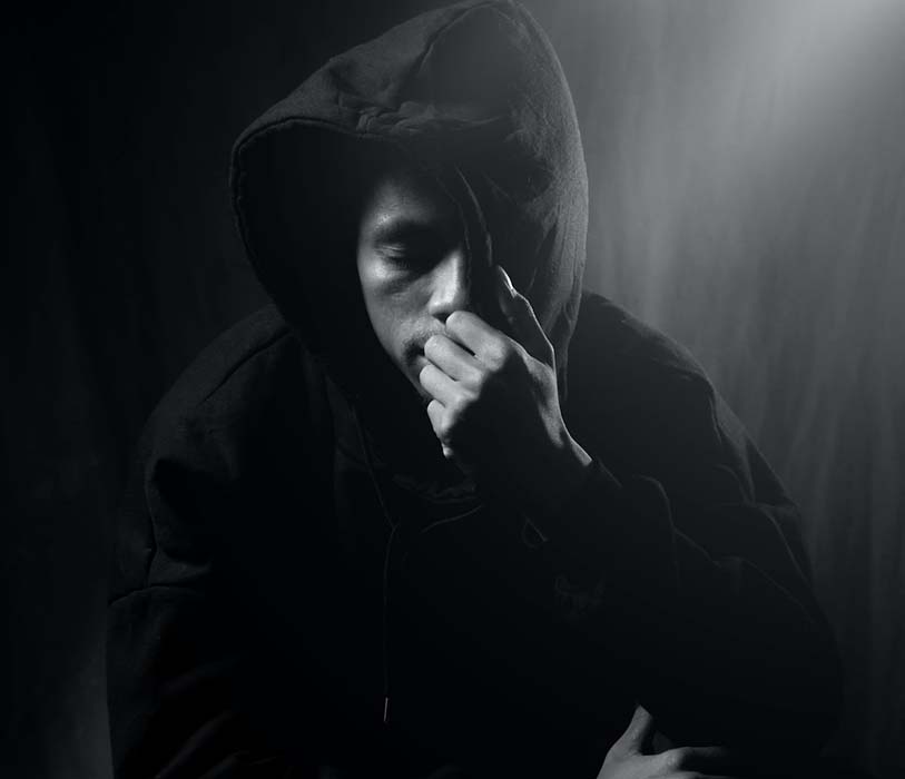 A man in hood in dark room