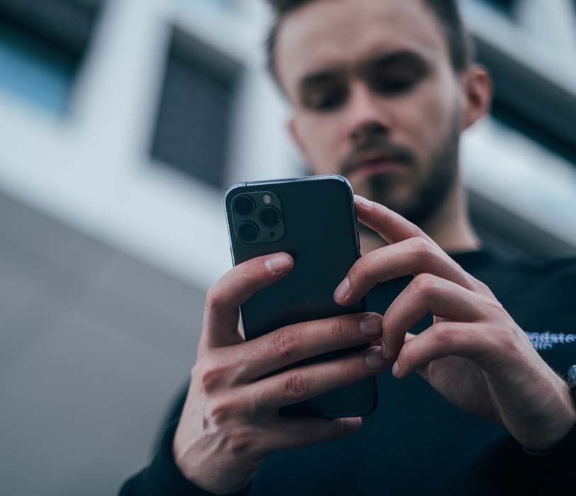 A man wearing a black sweater using a smartphone