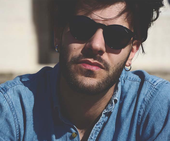 A man wearing a blue denim top and black sunglasses