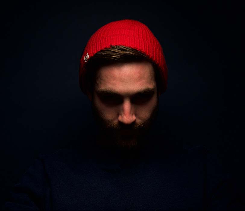 A man wearing red knit cap in dark a room