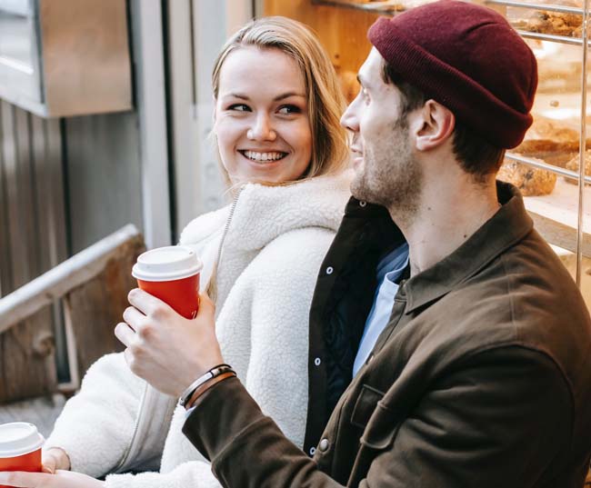 A positive young man and woman drinking coffee in coffee shop