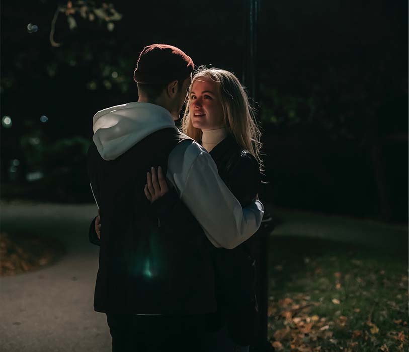 A romantic couple hugging in a park at night