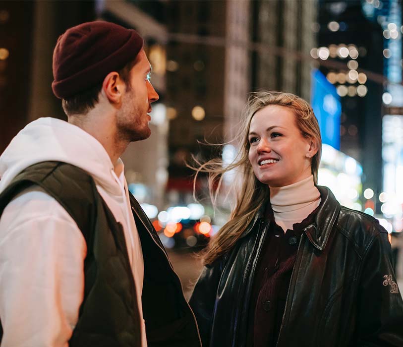 A romantic couple standing on the street laughing to each other