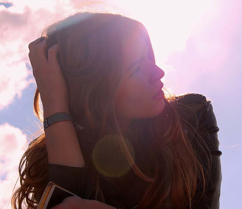 A woman in a black top holding her hair looking up