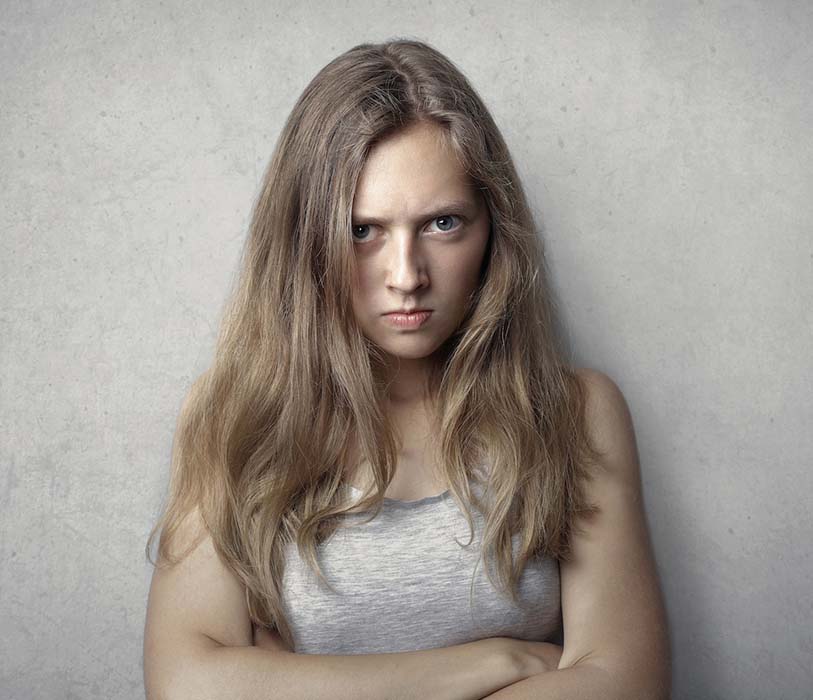 A woman in a gray tank top with an angry look