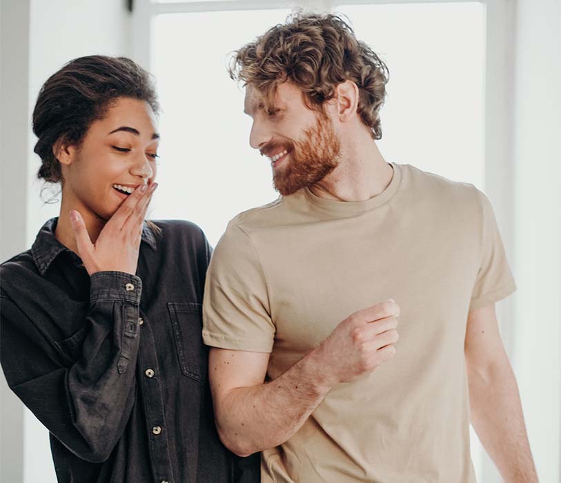 A woman in black button up shirt beside man in brown crew neck t-shirt