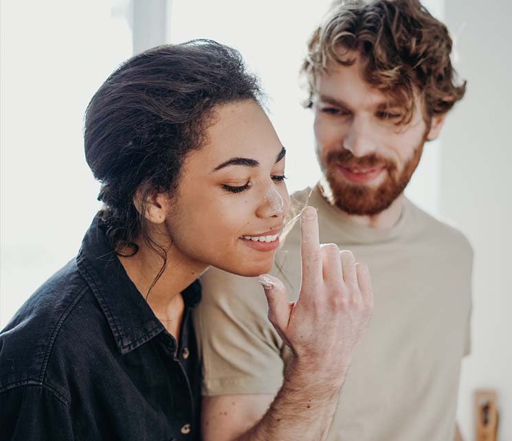 A woman in black denim jacket beside a man in beige crew neck shirt