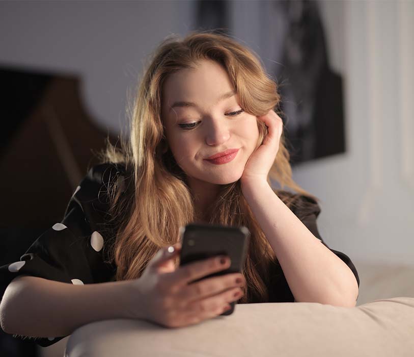 A woman in black polka dot shirt using a black smartphone