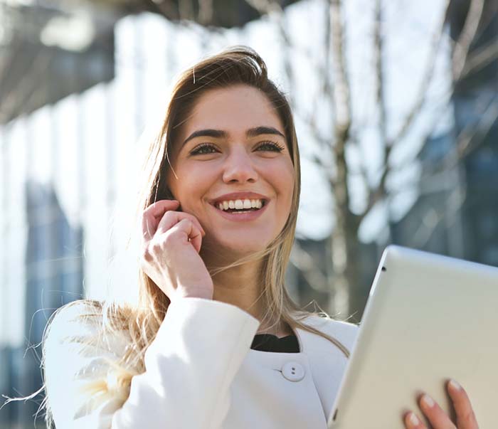 A woman in white blazer holding a tablet computer