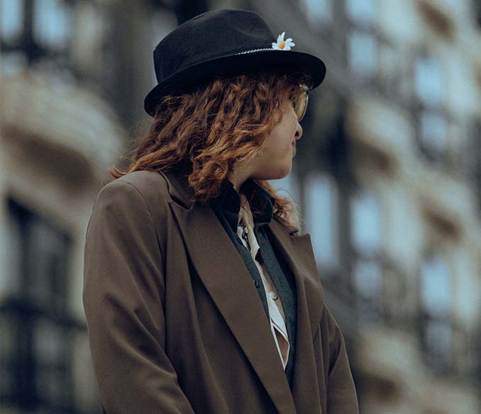 A woman wearing a brown blazer and a hat