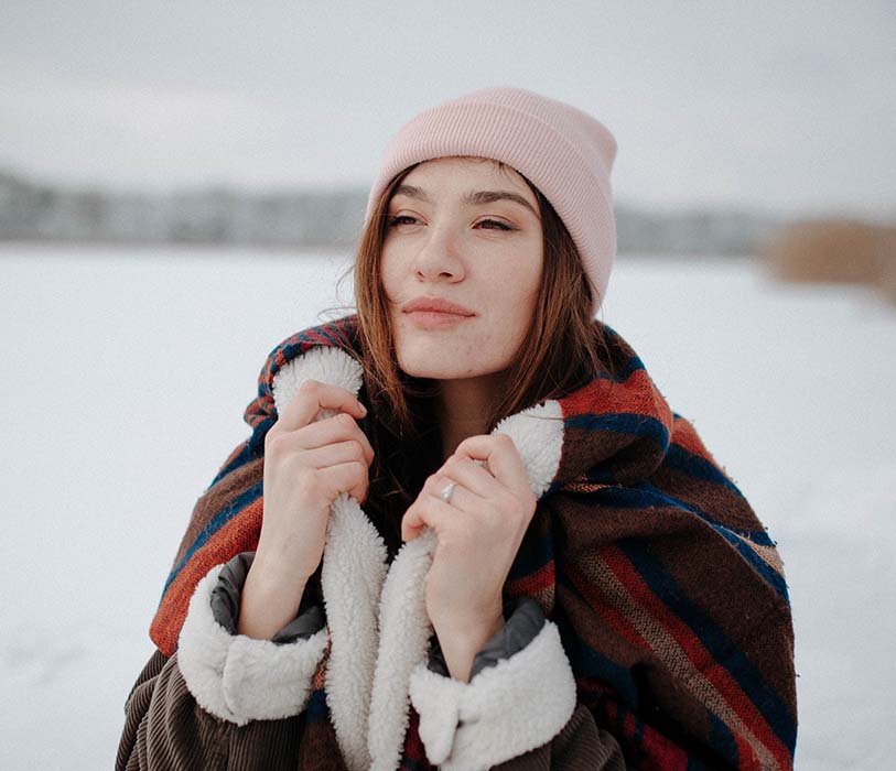 A woman wearing brown jacket and pink beanie with scarf