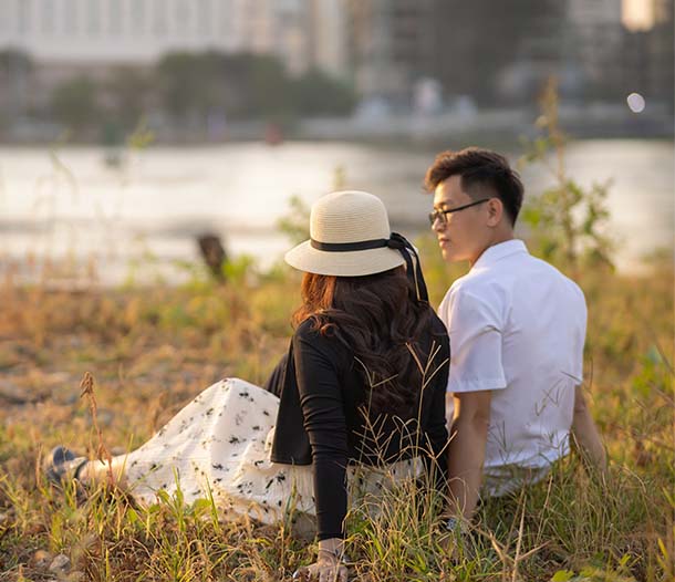 A young couple sitting together on the grass at dusk