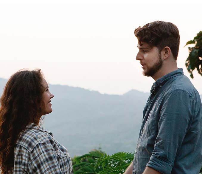 A young couple smiling while resting in woods in mountainous terrain