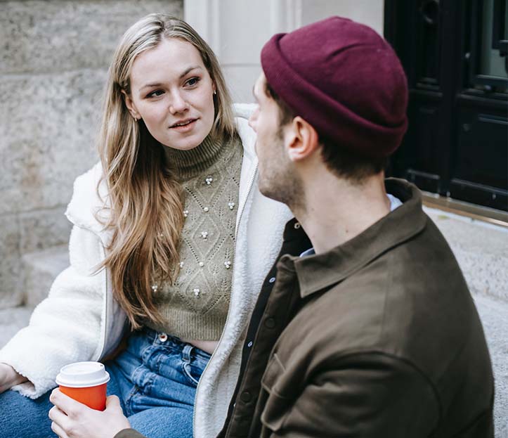 A young couple talking and drinking beverages on stairs