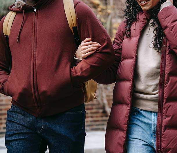 Crop multiethnic couple walking on city street