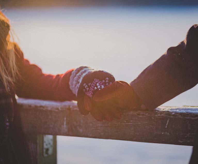 On a winter's day, young lovers hands touch on a cabin railing