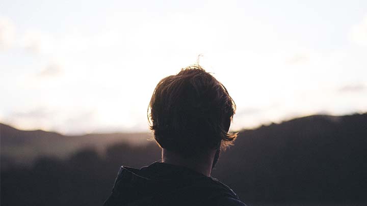 a person wearing a hoodie watching a mountain view