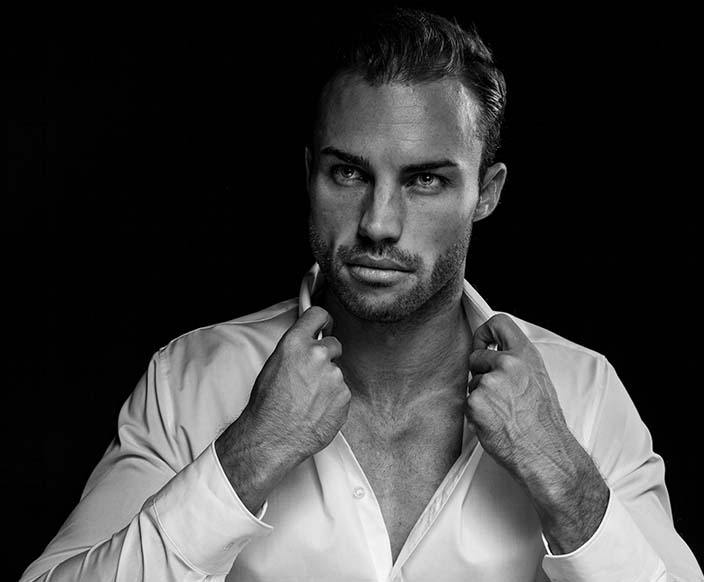 a grayscale portrait of a man wearing white dress shirt on black background