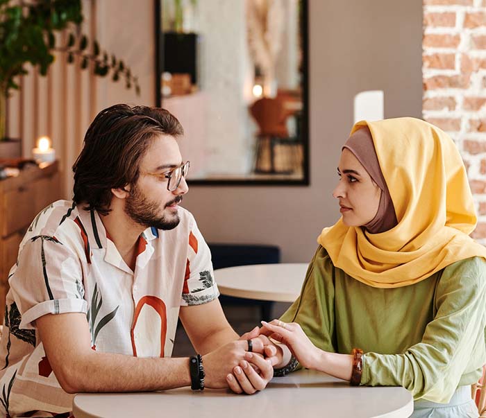 bearded man holding the hands of a woman wearing hijab