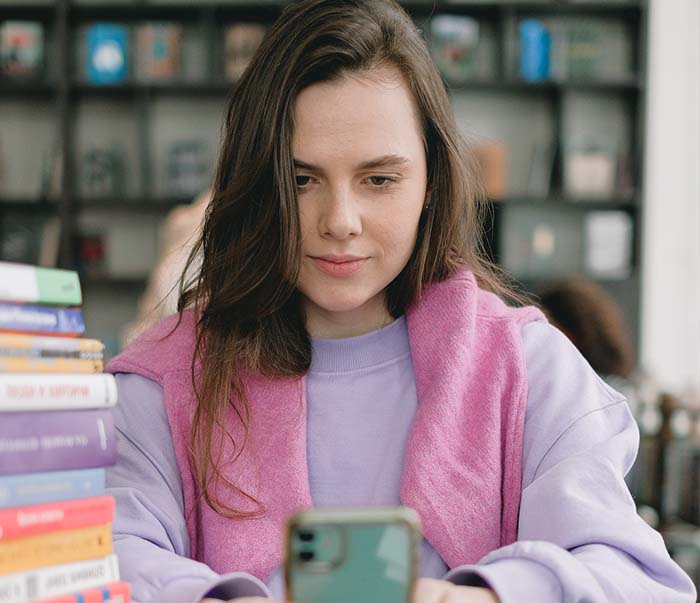 content student with smartphone in library