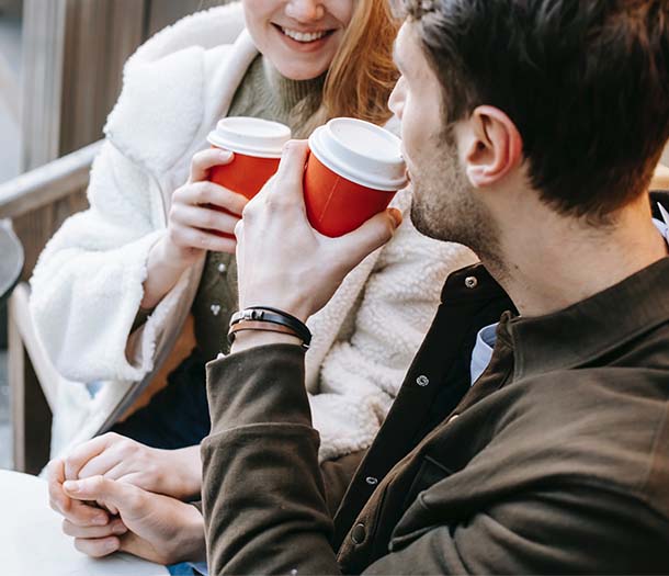 crop lady and guy communicating- while drinking takeaway beverages and holding hand