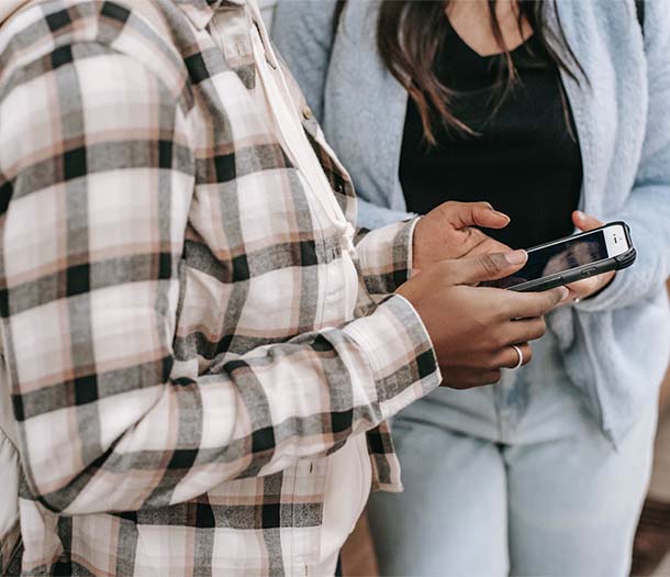 faceless female friends chatting on smartphone with black screen