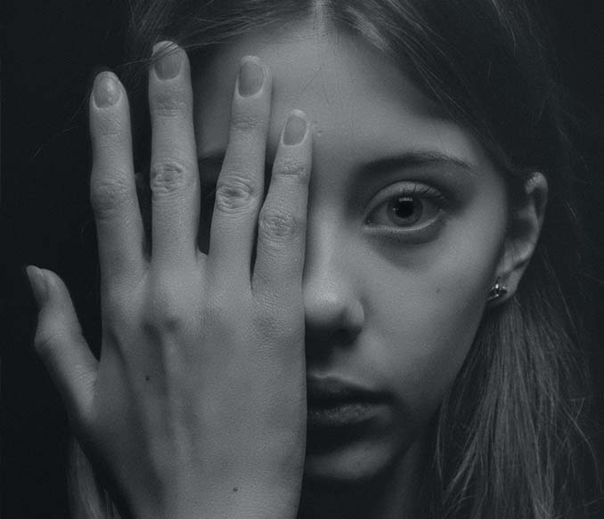 grayscale photo of woman covering her face by her hand