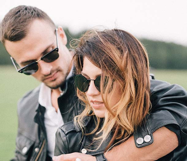 handsome man cuddling stylish girlfriend in sunglasses in countryside