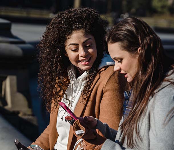 happy women using smartphone on city street on spring